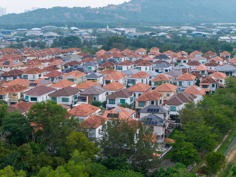 Aerial view of a residential neighborhood featuring houses with red tiled roofs and solar panels surrounded by lush greenery Central Seberang Perai Penang Malaysia.