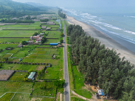 Aerial view of the Marine Drive road running alongside the sandy beach and sea waves with lush green fields and trees in Cox s Bazar Chittagong Division Bangladesh. Aerial view of the Marine Drive road running alongside the sandy beach and sea waves with lush green fields and trees in Cox s Bazar Chittagong Division Bangladesh.