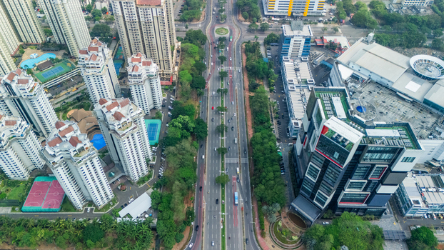 Aerial view of modern high rise apartment buildings and a busy multi lane road with lush trees and office complexes in Jakarta Indonesia. Aerial view of modern high rise apartment buildings and a busy multi lane road with lush trees and office complexes in Jakarta Indonesia.