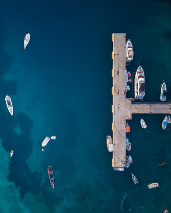 Aerial view of a stone pier with moored yachts and motorboats in deep blue turquoise water Porto Palermo Qarku i Vlores Albania. Aerial view of a stone pier with moored yachts and motorboats in deep blue turquoise water Porto Palermo Qarku i Vlores Albania.