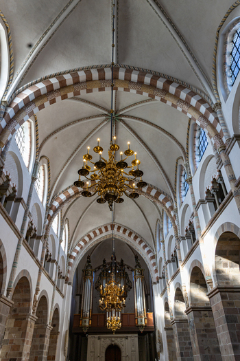 View of the interior of Ribe Cathedral featuring vaulted ceilings with striped arches golden chandeliers and a pipe organ Ribe Denmark. View of the interior of Ribe Cathedral featuring vaulted ceilings with striped arches golden chandeliers and a pipe organ Ribe Denmark.