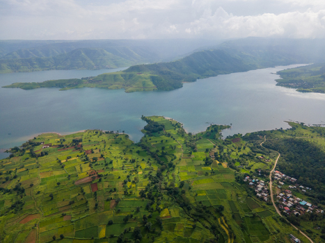 Aerial view of Kaas plateau featuring lush green agricultural fields rolling hills and the expansive blue waters of the Koyna reservoir in Satara Maharashtra India.