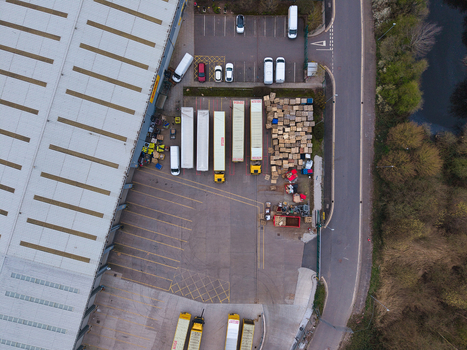 Aerial view of trucks lined up at a distribution center contrasting the industrial gray with the green of the surrounding trees Northampton United Kingdom. Aerial view of trucks lined up at a distribution center contrasting the industrial gray with the green of the surrounding trees Northampton United Kingdom.