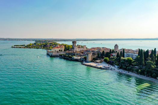 Aerial view of the Scaligero Castle and the historic peninsula of Sirmione on the turquoise waters of Lake Garda in Italy. Aerial view of the Scaligero Castle and the historic peninsula of Sirmione on the turquoise waters of Lake Garda in Italy.