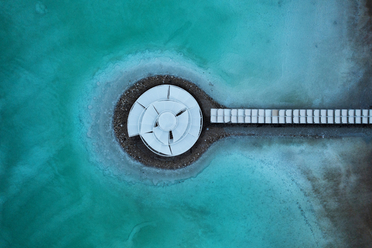Aerial view of a circular structure with a walkway extending into turquoise waters a serene contrast of geometric forms and natural hues Arad South District Israel. Aerial view of a circular structure with a walkway extending into turquoise waters a serene contrast of geometric forms and natural hues Arad South District Israel.