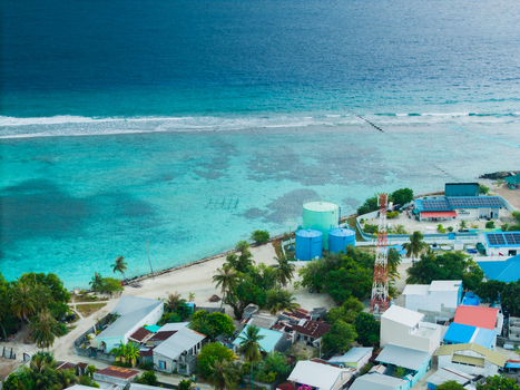 Aerial view of the turquoise waters meeting the sandy shores of Vashafaru Island with buildings nestled amongst the greenery Vashafaru Island Thiladhummathi Atoll Maldives. Aerial view of the turquoise waters meeting the sandy shores of Vashafaru Island with buildings nestled amongst the greenery Vashafaru Island Thiladhummathi Atoll Maldives.