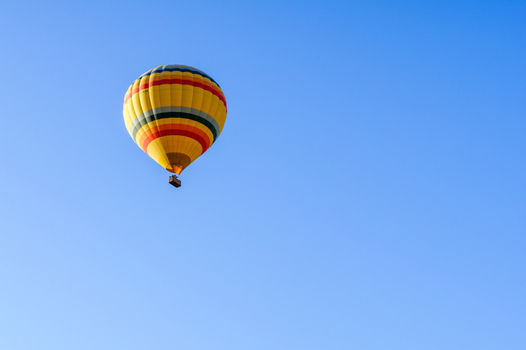 Aerial view of a colorful yellow hot air balloon floating in a clear blue sky over Cappadocia Kayseri Kayseri Turkiye. Aerial view of a colorful yellow hot air balloon floating in a clear blue sky over Cappadocia Kayseri Kayseri Turkiye.
