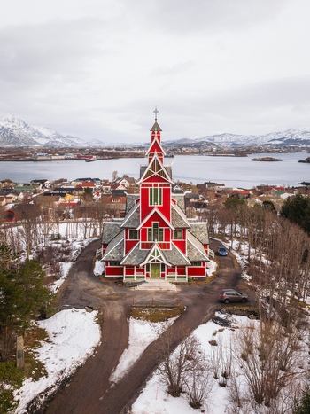 Aerial view of the vibrant red Buksnes Church stands tall against the muted winter landscape a beacon of color in the serene coastal town Gravdal Nordland Norway. Aerial view of the vibrant red Buksnes Church stands tall against the muted winter landscape a beacon of color in the serene coastal town Gravdal Nordland Norway.