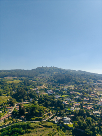 Aerial view of Pousada Mosteiro de Guimaraes situated on the lush green slopes of Monte da Penha surrounded by residential houses and dense forest in Guimaraes Braga Portugal. Aerial view of Pousada Mosteiro de Guimaraes situated on the lush green slopes of Monte da Penha surrounded by residential houses and dense forest in Guimaraes Braga Portugal.
