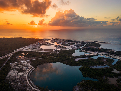 Aerial view of Cap Cana Marina at sunset featuring calm turquoise lagoons lush tropical vegetation and modern waterfront architecture in Punta Cana La Altagracia Province Dominican Republic.