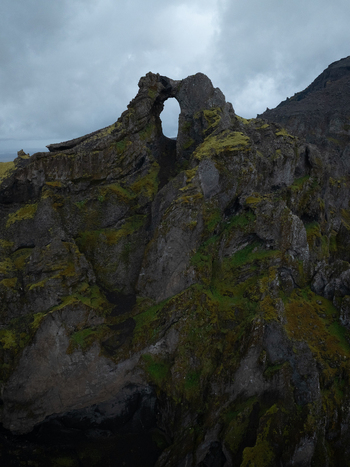 Aerial view of the natural stone arch at Kerlingarfjoll with rugged moss covered mountain peaks under a cloudy sky in Hrunamannahreppur Iceland. Aerial view of the natural stone arch at Kerlingarfjoll with rugged moss covered mountain peaks under a cloudy sky in Hrunamannahreppur Iceland.