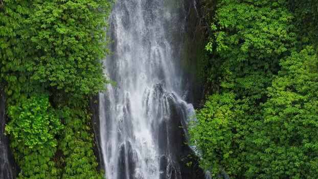 Aerial view of waterfall in lush tropical forest Indonesia.