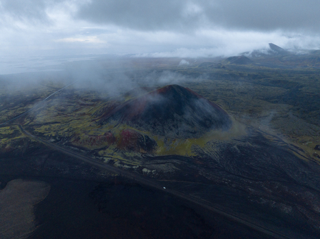 Aerial view of a volcanic landscape where black lava fields meet vividly colored moss under a cloudy sky Snæfellsnes Iceland. Aerial view of a volcanic landscape where black lava fields meet vividly colored moss under a cloudy sky Snæfellsnes Iceland.