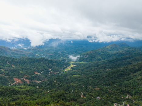 Aerial view of lush green mountains and a winding road through a misty valley under a cloudy sky Gampola Central Province Sri Lanka. Aerial view of lush green mountains and a winding road through a misty valley under a cloudy sky Gampola Central Province Sri Lanka.