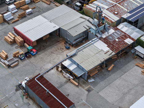 Melbourne Australia 25 September 2026 Aerial view of industrial factory site with stacks of lumber wood processing machinery and metal warehouse buildings.