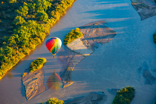 Albuquerque United States 11 October 2017 View of a hot air balloon drifting over the Rio Grande its vibrant colors mirroring the golden hues of the autumnal trees dotting the riverbank. Albuquerque United States 11 October 2017 View of a hot air balloon drifting over the Rio Grande its vibrant colors mirroring the golden hues of the autumnal trees dotting the riverbank.