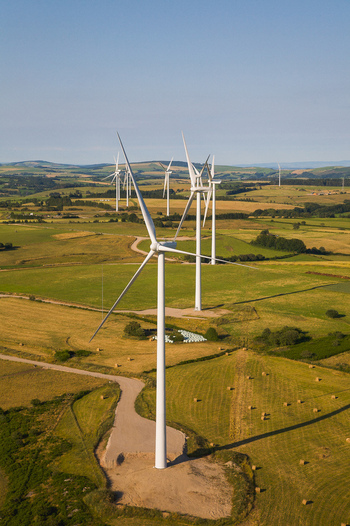 Aerial view of wind turbines standing tall against the undulating landscape their sleek white forms contrasting with the patchwork of golden fields and verdant hills Salles Curan Occitanie France. Aerial view of wind turbines standing tall against the undulating landscape their sleek white forms contrasting with the patchwork of golden fields and verdant hills Salles Curan Occitanie France.