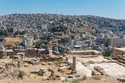 View of the historic Amman Citadel ruins with stone columns and ancient walls overlooking the dense urban cityscape of Amman Amman Governorate Jordan.