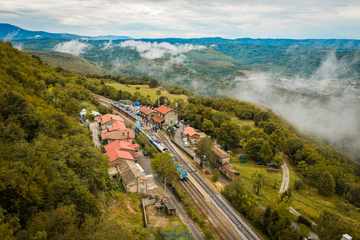Aerial view of the train station in Buzet surrounded by lush green hills dense forests and patches of morning fog in Buzet Istria County Croatia.