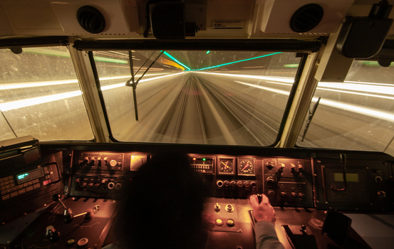 View of a train cockpit at night with the driver s hand on the controls and light trails visible through the window while in a tunnel at Schiphol Noord Holland Netherlands. View of a train cockpit at night with the driver s hand on the controls and light trails visible through the window while in a tunnel at Schiphol Noord Holland Netherlands.