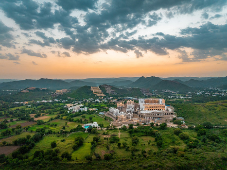 Aerial view of a large hotel complex nestled among the rolling green hills and fields of Udaipur Rajasthan India.