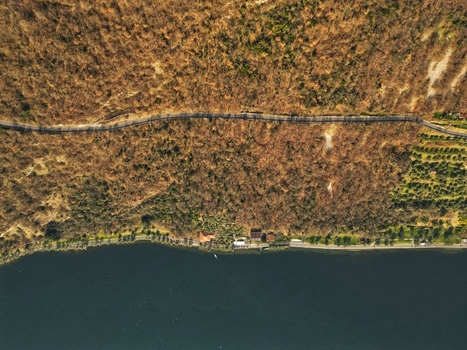 Aerial view of a winding road through a dense forest along the shoreline of Lake Iseo at Monte Isola Lombardy Italy. Aerial view of a winding road through a dense forest along the shoreline of Lake Iseo at Monte Isola Lombardy Italy.