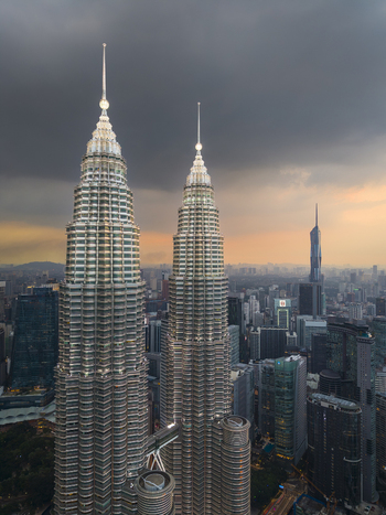 Kuala Lumpur Malaysia 11 March 2026 Aerial view of the Petronas Twin Towers with illuminated spires against a dramatic sunset sky and the city skyline.