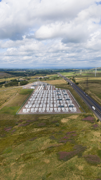 Aerial view of a large battery energy storage system facility with rows of white containers next to a highway in a rural landscape in Coalburn Scotland United Kingdom.