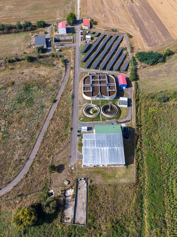 Aerial view of the sewage treatment plant featuring circular sedimentation tanks solar panels and industrial buildings surrounded by fields in Targu Secuiesc Covasna County Romania.