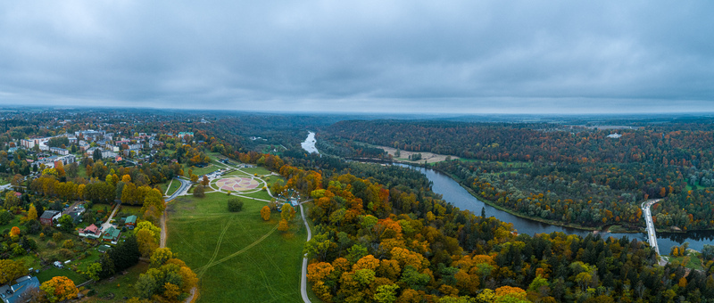 Aerial view of the town and the winding Gauja river surrounded by vibrant autumn forests under a cloudy sky in Sigulda Sigulda Municipality Latvia. Aerial view of the town and the winding Gauja river surrounded by vibrant autumn forests under a cloudy sky in Sigulda Sigulda Municipality Latvia.