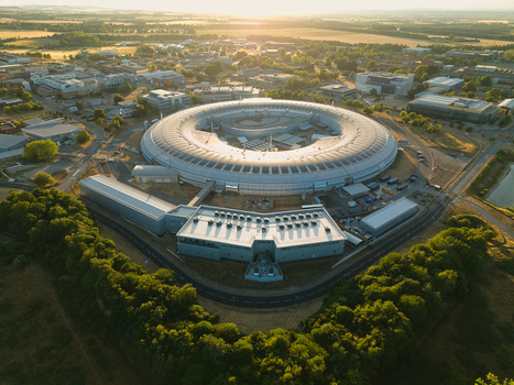 Aerial view of Diamond Light Source a circular synchrotron facility surrounded by greenery under golden hour light in Didcot United Kingdom.
