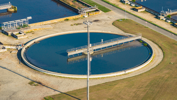 Aerial view of a large circular clarifier with rotating bridge equipment at a wastewater treatment facility in Italy.