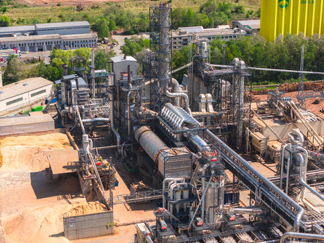 Aerial view of an industrial wood processing facility with complex machinery conveyor belts and large piles of sawdust in Jihlava Vysocina Region Czechia.