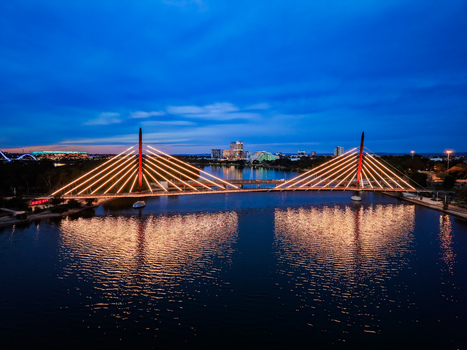 Aerial view of Boorloo Bridge illuminated at night over the Swan River with city skyline reflections and a blue twilight sky in East Perth Western Australia Australia.
