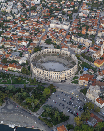 Aerial view of Pula Arena a historic Roman amphitheater surrounded by urban rooftops streets and greenery in Pula Istarska zupanija Croatia. Aerial view of Pula Arena a historic Roman amphitheater surrounded by urban rooftops streets and greenery in Pula Istarska zupanija Croatia.