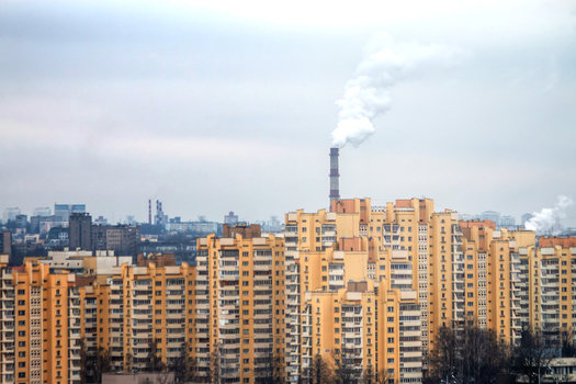 View of tall yellow apartment buildings in the city skyline with an industrial chimney emitting smoke under an overcast sky in Minsk Minsk Region Belarus. View of tall yellow apartment buildings in the city skyline with an industrial chimney emitting smoke under an overcast sky in Minsk Minsk Region Belarus.