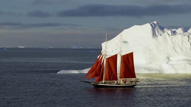 Aerial view of a sailboat with red sails near an iceberg Greenland. Aerial view of a sailboat with red sails near an iceberg Greenland.