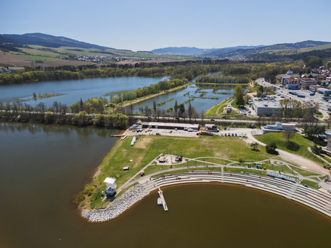 Aerial view of Oravska priehrada featuring a waterfront promenade with tiered stone seating green park area and rolling hills in Namestovo Zilinsky kraj Slovakia. Aerial view of Oravska priehrada featuring a waterfront promenade with tiered stone seating green park area and rolling hills in Namestovo Zilinsky kraj Slovakia.