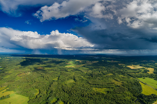 Aerial view of the lush green forests and agricultural fields of Latvia under a dramatic sky with heavy storm clouds and rain showers in the distance Latvia. Aerial view of the lush green forests and agricultural fields of Latvia under a dramatic sky with heavy storm clouds and rain showers in the distance Latvia.
