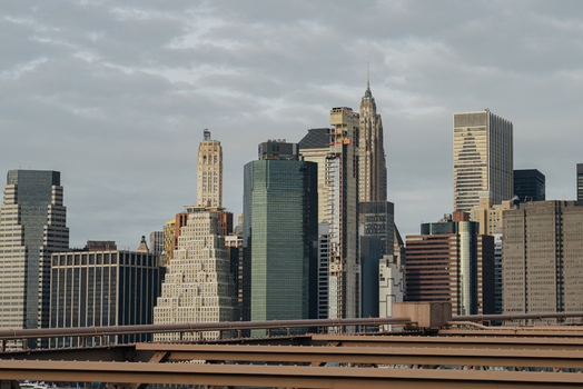 View of the Brooklyn Bridge with the New York City skyline in the background under a cloudy sky in New York New York United States.