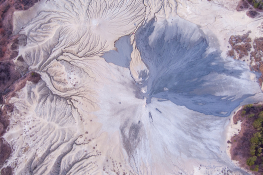 Aerial view of the Mud Volcanoes of Paclele Mari showing intricate grey mud flows eroded channels and barren landscape patterns in Paclele Buzau County Romania.