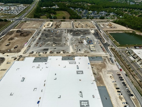 Aerial view of the construction site at Saint Johns Parkway and International Golf Parkway featuring a large white building and heavy machinery in World Golf Village Florida United States. Aerial view of the construction site at Saint Johns Parkway and International Golf Parkway featuring a large white building and heavy machinery in World Golf Village Florida United States.