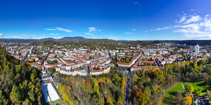 Aerial view of the terracotta rooftops contrasting with the lush autumnal foliage in Stadtpark city park and the distant mountain Sch&ouml;ckl Graz Styria Austria.