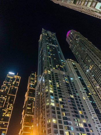View of illuminated skyscrapers in Dubai Marina at night featuring modern architectural glass facades and glowing windows in Dubai Dubai United Arab Emirates. View of illuminated skyscrapers in Dubai Marina at night featuring modern architectural glass facades and glowing windows in Dubai Dubai United Arab Emirates.