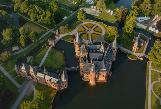 Aerial view of De Haar Castle with its majestic towers stone bridges and lush formal gardens surrounded by water moats during sunset in Utrecht Utrecht Netherlands. Aerial view of De Haar Castle with its majestic towers stone bridges and lush formal gardens surrounded by water moats during sunset in Utrecht Utrecht Netherlands.
