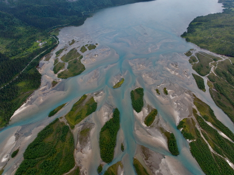Aerial view of a braided river system with glacial meltwater river islands and lush green vegetation surrounded by mountains in Skonseng Nordland Norway. Aerial view of a braided river system with glacial meltwater river islands and lush green vegetation surrounded by mountains in Skonseng Nordland Norway.