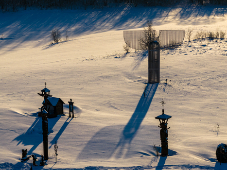 Aerial view of the Hill of Angels featuring wooden sculptures and a large metal angel casting long shadows on a snow covered field in Traku rajonas Vilniaus apskritis Lithuania. Aerial view of the Hill of Angels featuring wooden sculptures and a large metal angel casting long shadows on a snow covered field in Traku rajonas Vilniaus apskritis Lithuania.