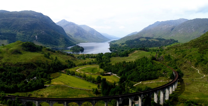 Aerial view of the iconic Glenfinnan Viaduct curving through the lush green Scottish Highlands with Loch Shiel in the background Glenfinnan Scotland United Kingdom. Aerial view of the iconic Glenfinnan Viaduct curving through the lush green Scottish Highlands with Loch Shiel in the background Glenfinnan Scotland United Kingdom.