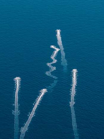 Aerial view of jet skis leaving white wakes on the deep blue Mediterranean Sea near Le Trayas Saint Raphael Provence Alpes Cote d Azur France. Aerial view of jet skis leaving white wakes on the deep blue Mediterranean Sea near Le Trayas Saint Raphael Provence Alpes Cote d Azur France.