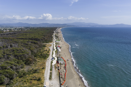 Aerial view of the long sandy coastline and dense pine forest bordering the turquoise Tyrrhenian Sea under a clear blue sky Paestum Campania Italy.